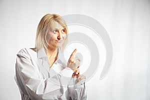 Portrait of a pretty blonde smiling woman posing on a white background and pointing somewhere. Happy girl model in white