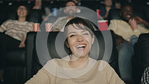 Portrait of pretty brunette having fun watching movie in cinema laughing