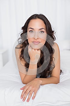 Portrait of a pretty brunette lying in bed