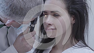 Portrait of pretty brunette smiling woman sitting in the chair of doctor oculist doing eye test. Professional