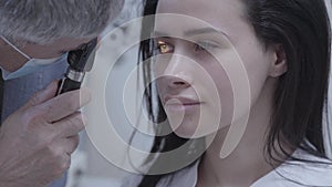 Portrait of pretty brunette woman sitting in the chair of doctor oculist doing eye test. Professional ophthalmologist