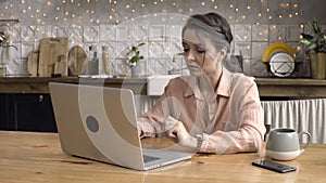 A portrait of pretty brunette woman typing email on laptop computer while sitting at home, freelance concept. Stock