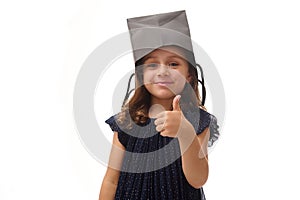 Portrait of pretty Caucasian girl having fun, putting a black shopping packet on her head, smiling looking at camera, showing