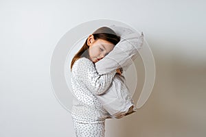 Portrait of pretty caucasian girl in white pyjama and pillow in studio white background