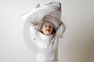 Portrait of pretty caucasian girl in white pyjama and pillow in studio white background