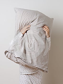 Portrait of pretty caucasian girl in white pyjama and pillow in studio white background