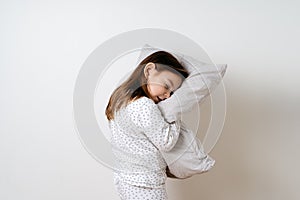 Portrait of pretty caucasian girl in white pyjama and pillow in studio white background