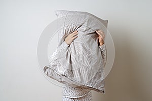 Portrait of pretty caucasian girl in white pyjama and pillow in studio white background