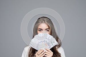 Portrait of pretty charming positive glad funny woman covering closing half face with fan from dollars looking out with eyes at ca