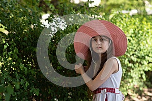 Portrait of pretty cheerful woman wearing white dress and straw pink hat in sunny warm weather day