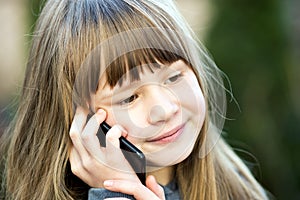 Portrait of pretty child girl with long hair talking on cell phone. Little female kid communicating using smartphone. Children