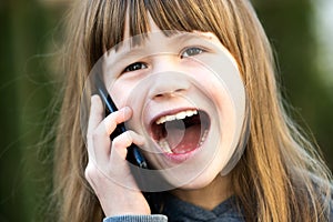 Portrait of pretty child girl with long hair talking on cell phone. Little female kid communicating using smartphone. Children