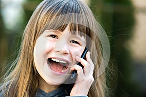 Portrait of pretty child girl with long hair talking on cell phone. Little female kid communicating using smartphone. Children