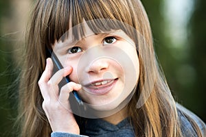 Portrait of pretty child girl with long hair talking on cell phone. Little female kid communicating using smartphone. Children