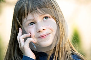 Portrait of pretty child girl with long hair talking on cell phone. Little female kid communicating using smartphone. Children