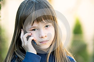 Portrait of pretty child girl with long hair talking on cell phone. Little female kid communicating using smartphone. Children