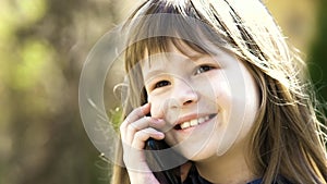 Portrait of pretty child girl with long hair talking on cell phone. Little female kid communicating using smartphone. Children com