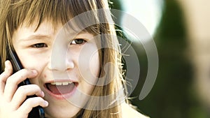 Portrait of pretty child girl with long hair talking on cell phone. Little female kid communicating using smartphone. Children com