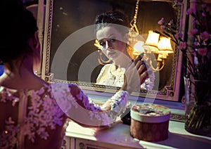 Portrait of a pretty countess touching an antique mirror
