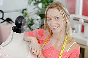 portrait pretty dressmaker leaning on mannequin