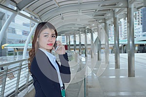 Portrait of pretty face young Asian business woman talking on phone at urban city background.
