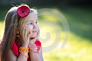 Portrait of pretty fashionable child girl in red dress enjoying warm sunny summer day