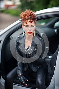 Beautiful young woman sitting in the white car with opened doors