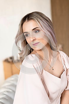 Portrait of a pretty girl with blond hair wearing a beige dress