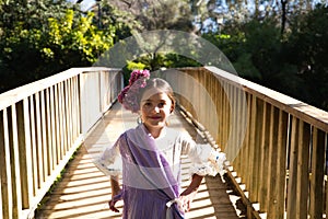 Portrait of a pretty girl dancing flamenco in a dress with frills and fringes typical of gypsies, walking on a wooden bridge in a photo