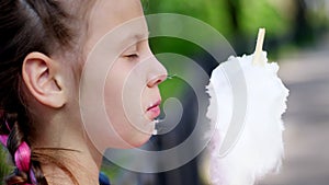 portrait, pretty girl of eight years, blonde, with freckles, and multi-colored pigtails, eats sweet white cotton, cotton