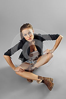 Portrait of a pretty girl in jeans shorts posing with hands on her knees