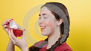 Portrait of a pretty girl opens a jar of jelly, sniffs and wants to try it. Yellow background. Sugar free desserts.