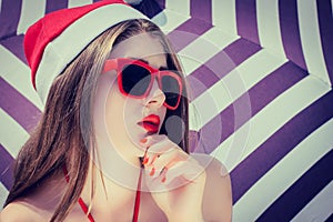 Portrait of a pretty girl in Santa Claus hat and red sunglasses