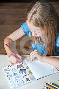 Portrait pretty girl sitting table with adult coloring book pencils .