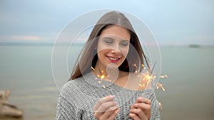 Portrait of pretty girl with sparkler looking at camera
