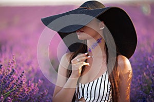 Portrait of pretty girl is wearing big hat sitting in lavender field, France.