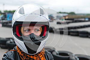 Portrait of a pretty girl wearing a white helmet close up, detail of Go-kart. karting track racing, copy space. serious look,