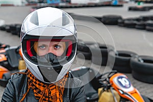 Portrait of a pretty girl wearing a white helmet close up, detail of Go-kart. karting track racing, copy space. serious look,