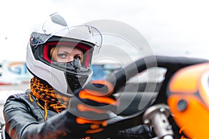 Portrait of a pretty girl wearing a white helmet close up, detail of Go-kart. karting track racing, copy space. serious look,