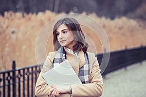 Portrait of pretty girl young woman with digital tablet looking away to the side outdoors park background