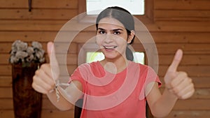 Portrait of a pretty Indian girl smiling and gesturing thumbs-ups at the camera