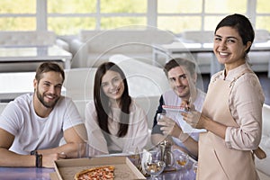 Portrait of pretty Indian waitress serving group of customers