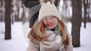 Portrait of pretty joyful Caucasian teen girl laughing sitting on sledge tossing white snow. Happy cute teenager posing