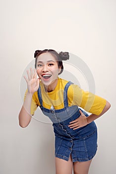 Portrait of pretty joyful woman with two buns holding hands at face and calling aside isolated over white background