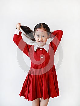 Portrait of pretty little child girl in princess dress with smiling and expression tying up her hair isolated on white background