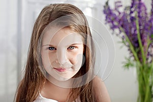 Portrait of pretty  little emotion girl  among violet flowers.Clouse up picture of beautiful smiling girl