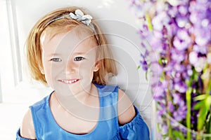 Portrait of pretty  little emotion girl  among violet flowers.Clouse up picture of beautiful smiling girl