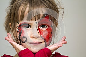 Portrait of pretty little girl with butterfly painting on her fa