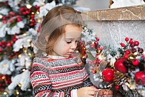 Portrait of pretty little girl looks at a Christmas toy at home