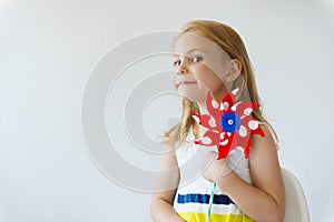 Portrait of pretty little girl with red windmill at summer day